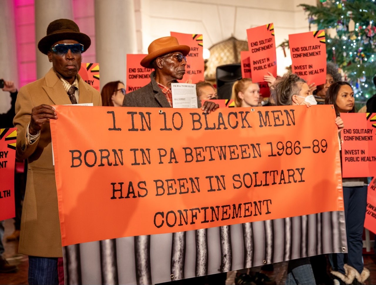 People hold sign stating, "1 in 10 Black men born in PA between 1986-89 has been in solitary confinement."